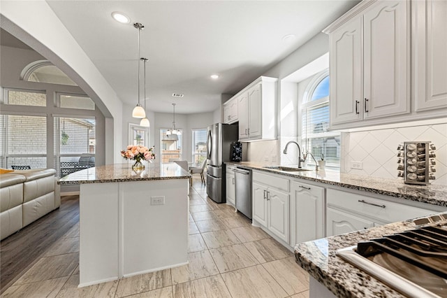 1036 Rutherford St, Frisco, TX 75036 - kitchen with a sink, stainless steel appliances, tasteful backsplash, white cabinetry, and a center island