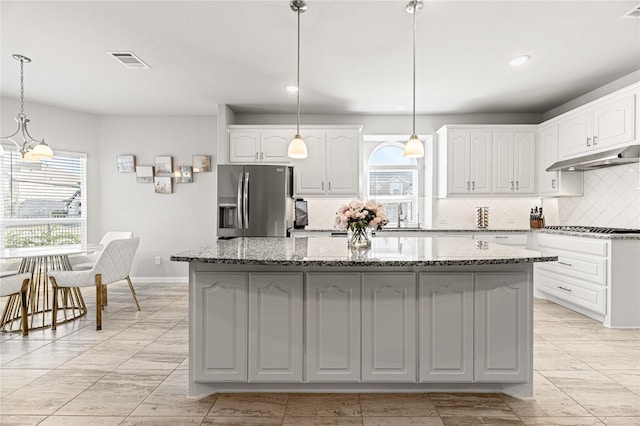 1036 Rutherford St, Frisco, TX 75036 - kitchen featuring stainless steel appliances, tasteful backsplash, light stone counters, visible vents, and under cabinet range hood