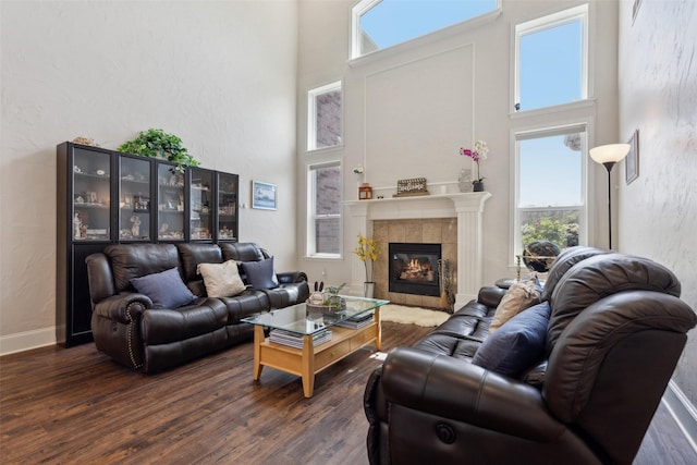 5205 Coral Springs Dr, Flower Mound, TX 75022 - living room featuring a high ceiling, dark wood finished floors, a tiled fireplace, a textured wall, and baseboards