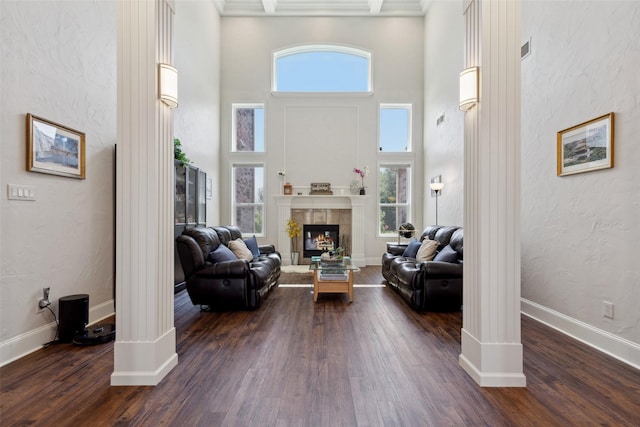 5205 Coral Springs Dr, Flower Mound, TX 75022 - living room featuring plenty of natural light, dark wood-style floors, a towering ceiling, a tiled fireplace, and baseboards