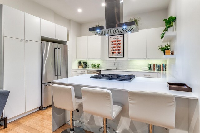 4401 Roseland Ave Unit A, Dallas, TX 75204 - kitchen featuring island range hood, a kitchen breakfast bar, a sink, and appliances with stainless steel finishes