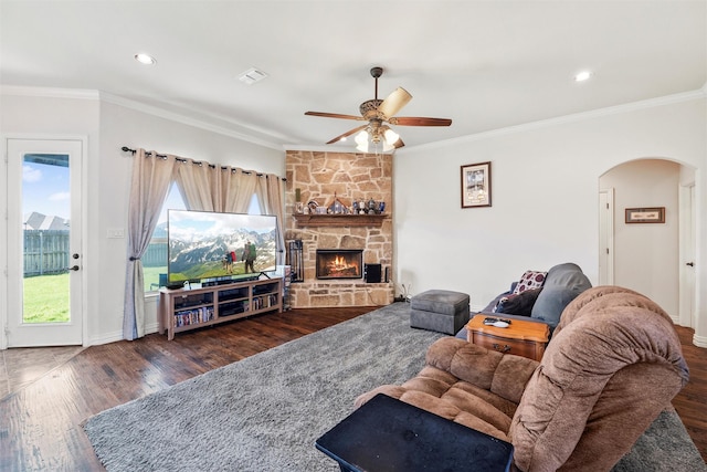 living area featuring ornamental molding, a ceiling fan, arched walkways, and wood finished floors