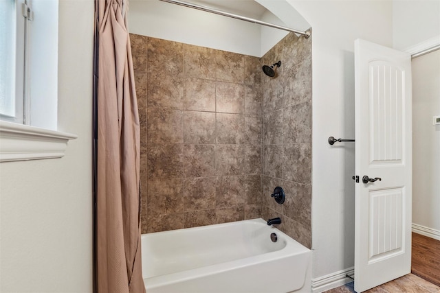 bathroom with shower / bath combo, wood finished floors, and baseboards