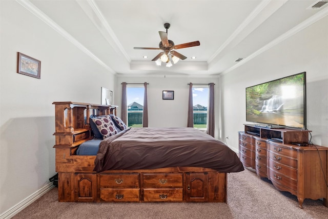 bedroom with light carpet, visible vents, a tray ceiling, and crown molding