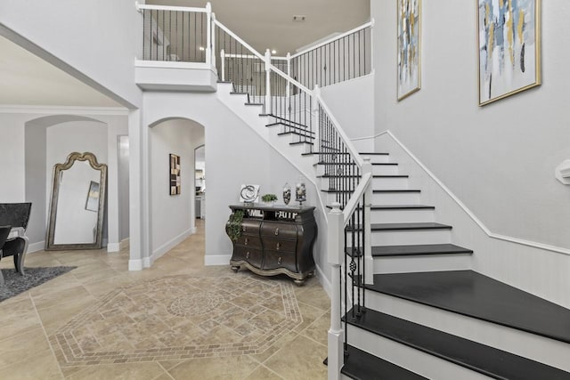847 Bentwater Pkwy, Grand Prairie, TX 75104 - staircase with arched walkways, a towering ceiling, baseboards, and tile patterned floors