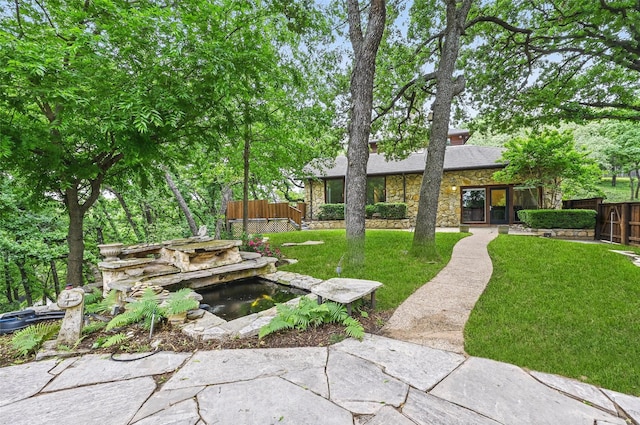 view of yard with fence and a garden pond