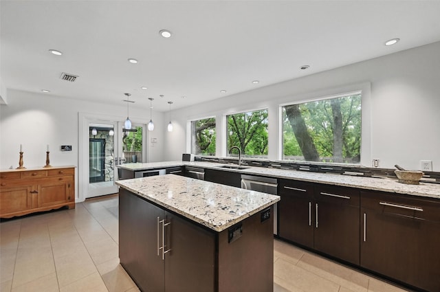 kitchen with a center island, a sink, light tile patterned floors, and light stone countertops