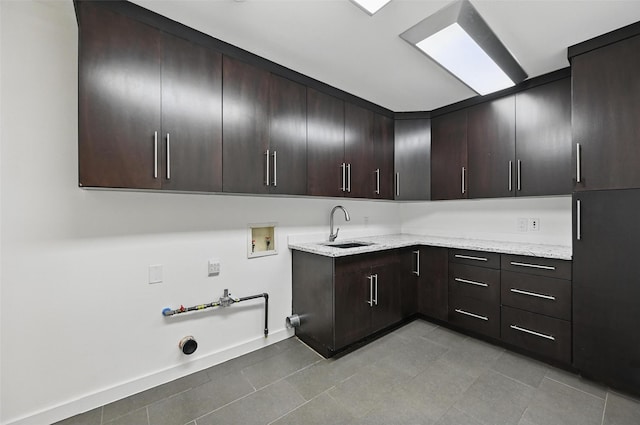 laundry room featuring cabinet space, a sink, hookup for a washing machine, gas dryer hookup, and light tile patterned floors
