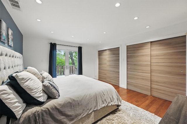bedroom featuring visible vents, access to exterior, wood finished floors, multiple closets, and recessed lighting