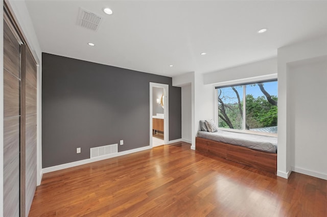 unfurnished bedroom with visible vents, recessed lighting, baseboards, and wood finished floors