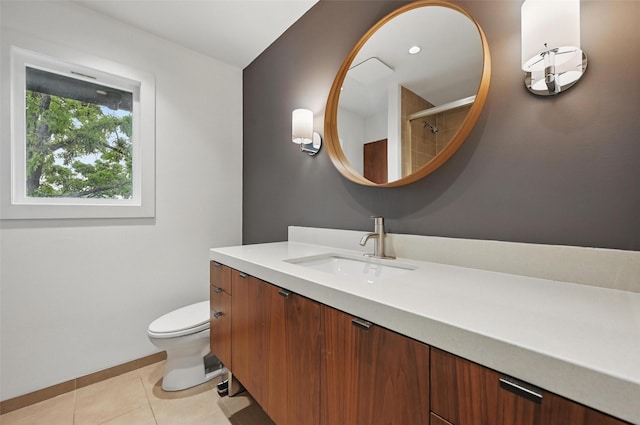 bathroom with tile patterned flooring, a tile shower, vanity, baseboards, and toilet