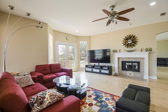 232 Wilshire Dr, Coppell, TX 75019 - living area with ceiling fan, arched walkways, visible vents, wood finished floors, and a tile fireplace