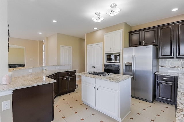 232 Wilshire Dr, Coppell, TX 75019 - kitchen with white cabinets, a center island, light stone counters, stainless steel appliances, and decorative backsplash