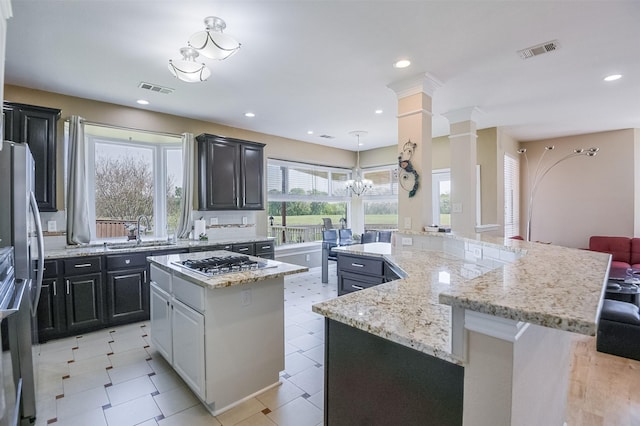 232 Wilshire Dr, Coppell, TX 75019 - kitchen featuring visible vents, a sink, ornate columns, stainless steel appliances, and a kitchen island