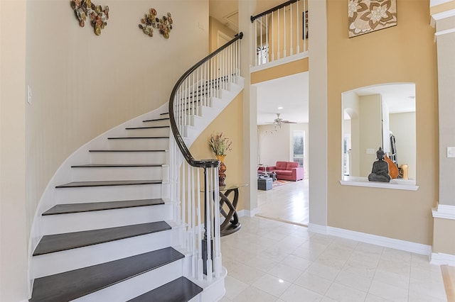 232 Wilshire Dr, Coppell, TX 75019 - stairs featuring arched walkways, a towering ceiling, baseboards, and a ceiling fan