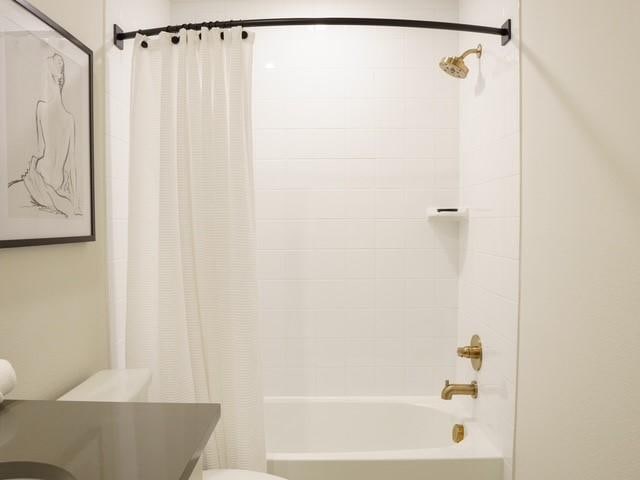 bathroom with shower / bath combo with shower curtain, toilet, and vanity
