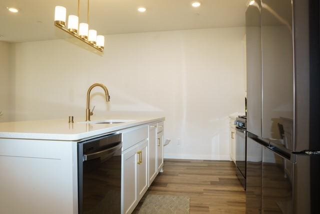 kitchen featuring freestanding refrigerator, light wood-style floors, white cabinets, a sink, and dishwashing machine