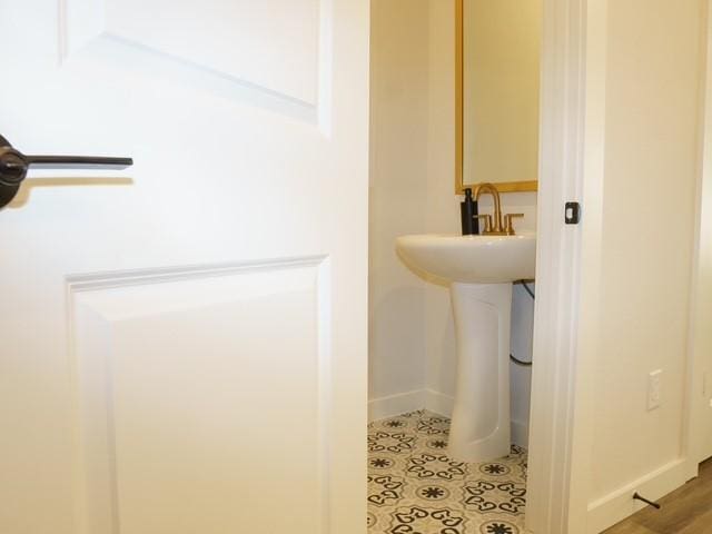bathroom with baseboards, tile patterned flooring, and a sink