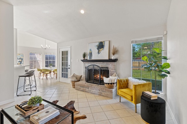 living room featuring a healthy amount of sunlight, vaulted ceiling, an inviting chandelier, a fireplace, and light tile patterned floors
