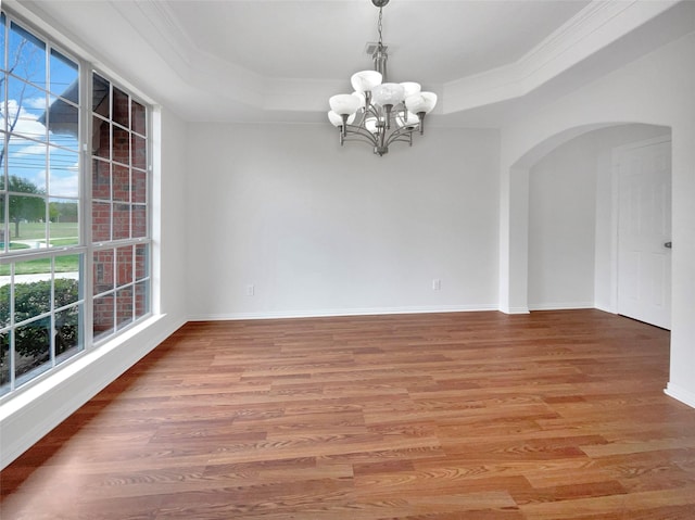 unfurnished room featuring plenty of natural light, a tray ceiling, an inviting chandelier, and wood finished floors