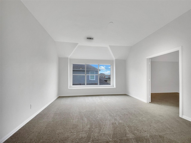 spare room featuring visible vents, baseboards, carpet, and lofted ceiling