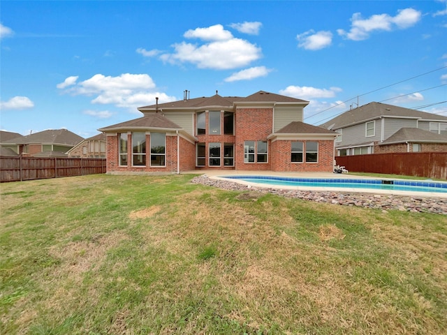 back of house featuring a fenced in pool, a yard, brick siding, and fence