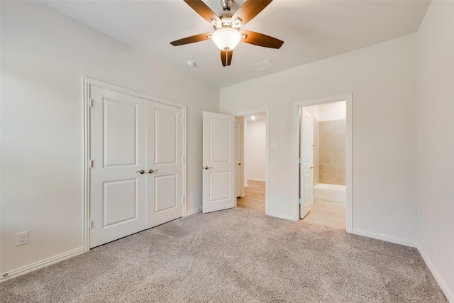 unfurnished bedroom with light colored carpet, baseboards, ensuite bath, and a closet