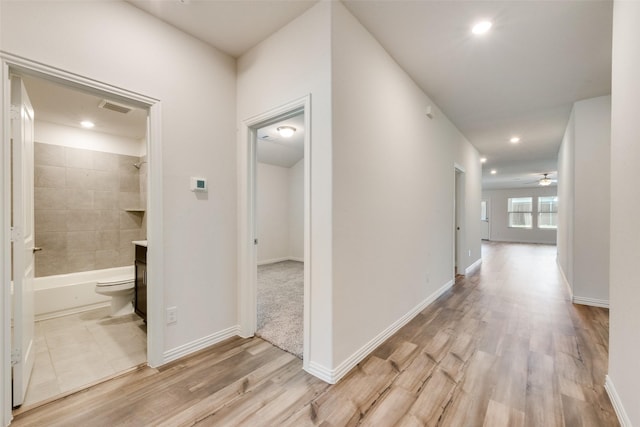 hallway featuring recessed lighting, light wood-type flooring, visible vents, and baseboards