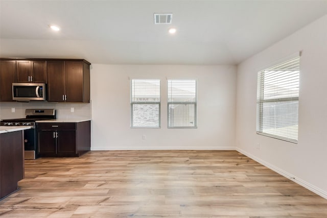 kitchen with light wood finished floors, stainless steel appliances, light countertops, visible vents, and dark brown cabinetry