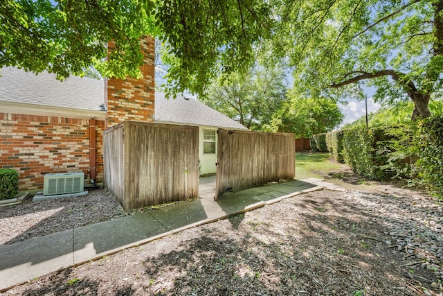 view of outbuilding with a fenced backyard and central AC unit