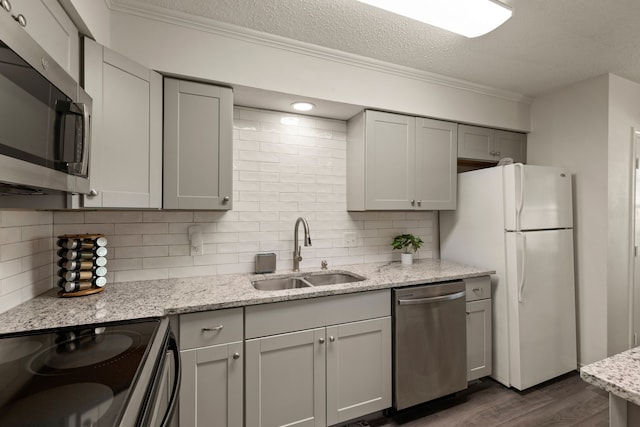 kitchen with ornamental molding, a sink, dark wood-type flooring, tasteful backsplash, and appliances with stainless steel finishes