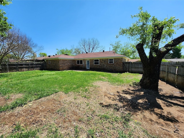 rear view of house with a yard, brick siding, and a fenced backyard