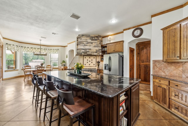 kitchen with open shelves, arched walkways, stainless steel refrigerator with ice dispenser, and ornamental molding