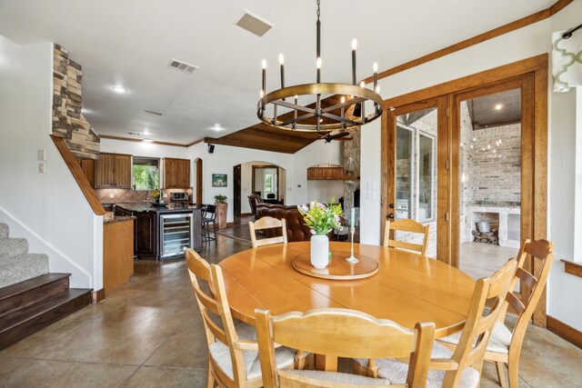 dining space with beverage cooler, stairway, visible vents, arched walkways, and a chandelier