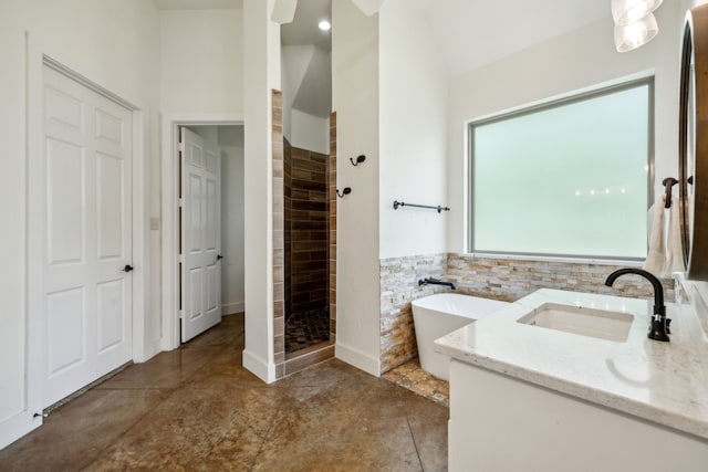 full bathroom with a shower stall, a freestanding tub, and vanity