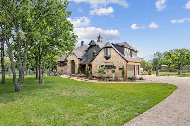 french provincial home with a chimney, driveway, stone siding, an attached garage, and fence