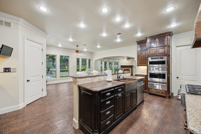 4401 Sorrel Ct, Flower Mound, TX 75028 - kitchen featuring arched walkways, a ceiling fan, a warming drawer, a sink, and ornamental molding