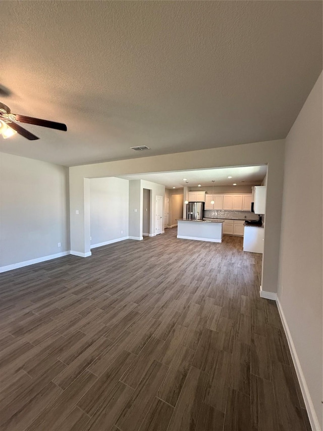 unfurnished living room featuring dark wood-style floors, baseboards, and a ceiling fan