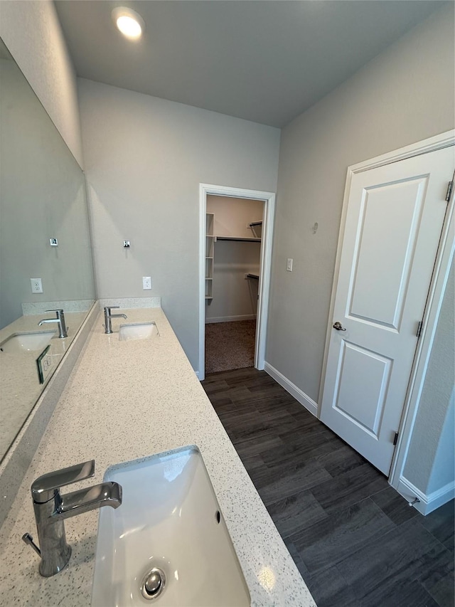 full bathroom featuring a walk in closet, a sink, and wood finished floors