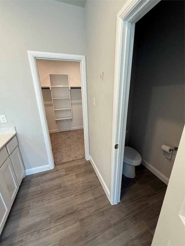 bathroom featuring toilet, wood finished floors, vanity, and baseboards