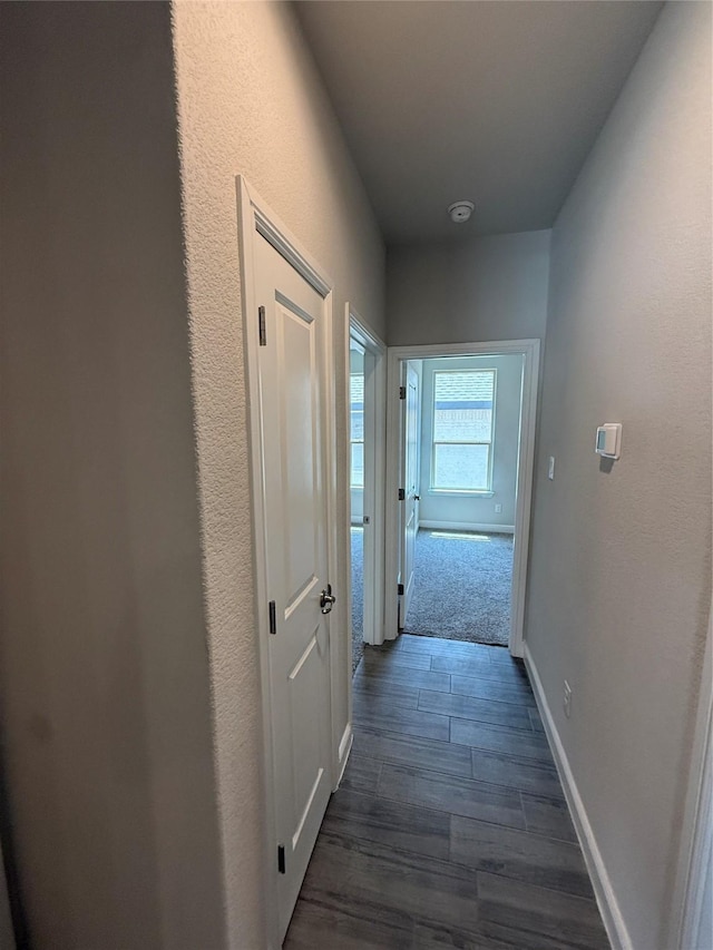hall with dark wood-style flooring and baseboards