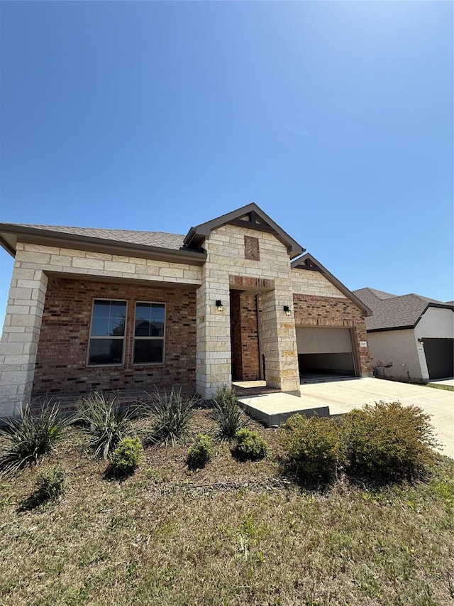 view of front of house with brick siding, a garage, driveway, and roof with shingles