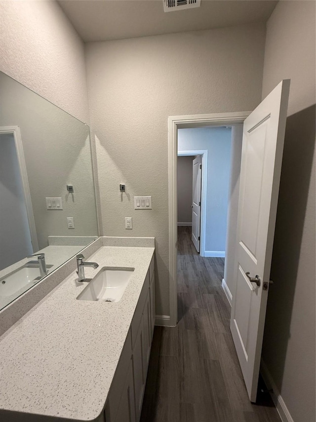 bathroom with wood finished floors, vanity, baseboards, and visible vents