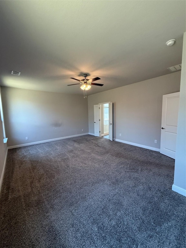 empty room featuring visible vents, baseboards, and dark carpet