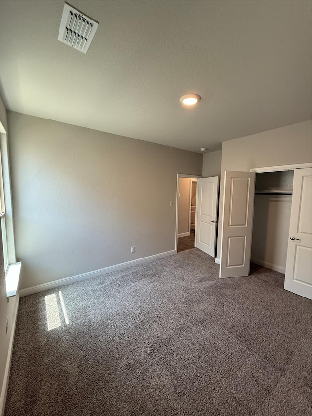 unfurnished bedroom featuring a closet, carpet, visible vents, and baseboards