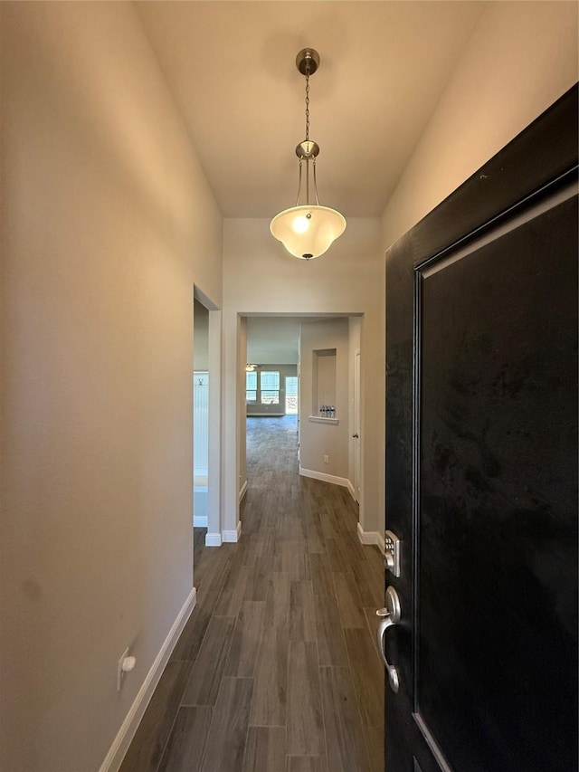 corridor with dark wood-type flooring and baseboards
