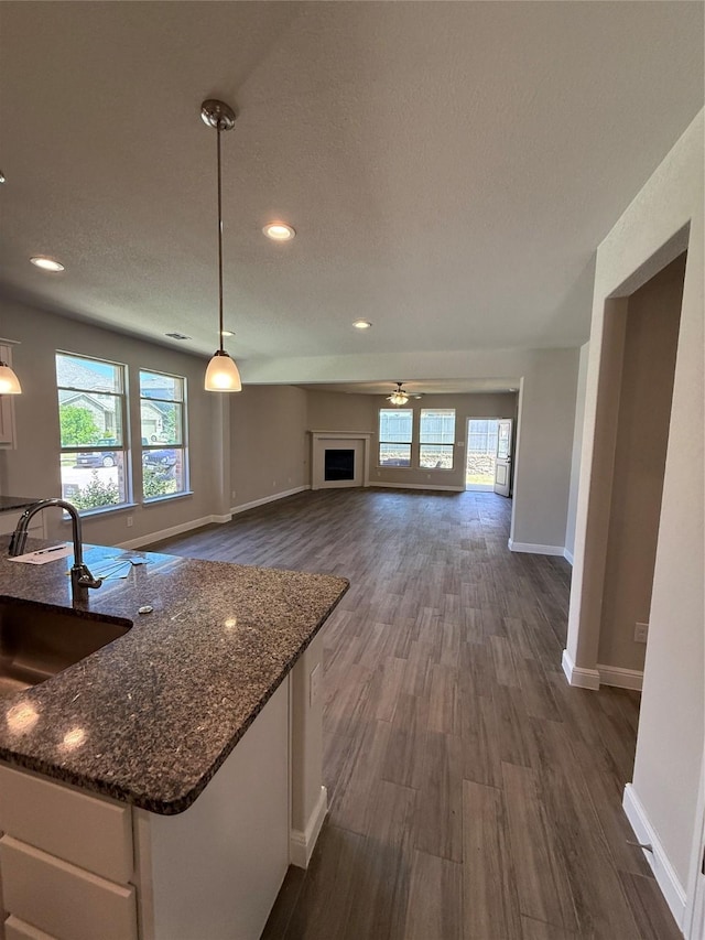 kitchen featuring a sink, baseboards, dark stone countertops, and a healthy amount of sunlight