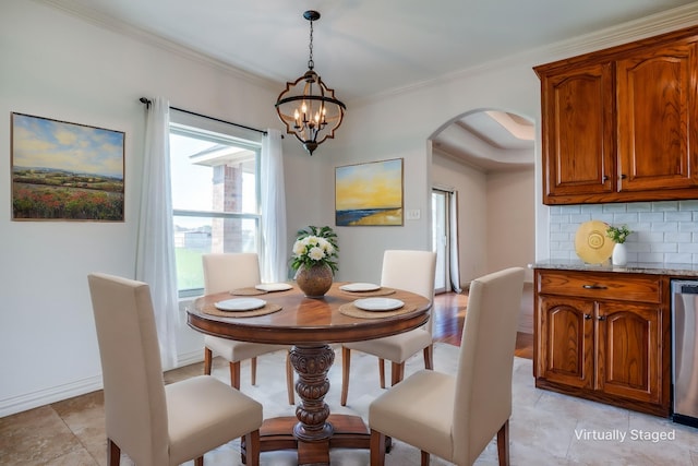 dining room with arched walkways, a healthy amount of sunlight, a notable chandelier, and crown molding