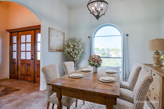 dining area with arched walkways, an inviting chandelier, a high ceiling, and crown molding