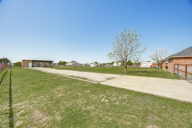 view of yard featuring fence, an outbuilding, and driveway